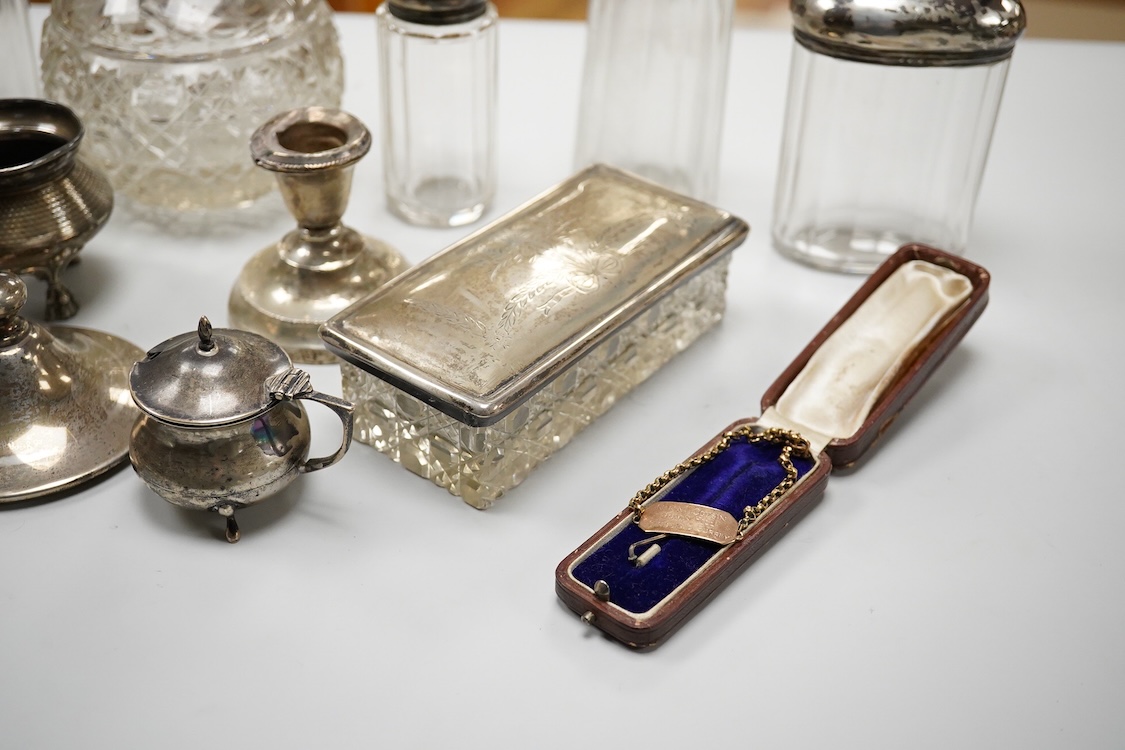 An early 20th century silver mounted cut glass scent bottle, five silver mounted glass toilet jars, a pair of silver mounted dwarf candlesticks, two silver condiments, a sterling jug(weighted), a sterling cup and cover(w